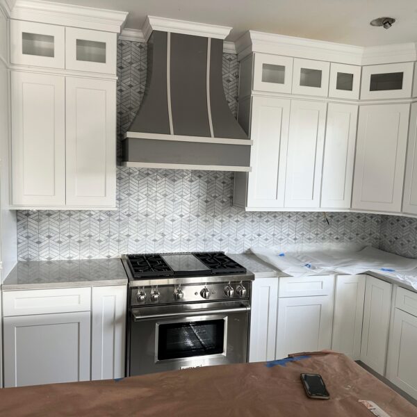 Gray custom wood range hood with decorative metal straps